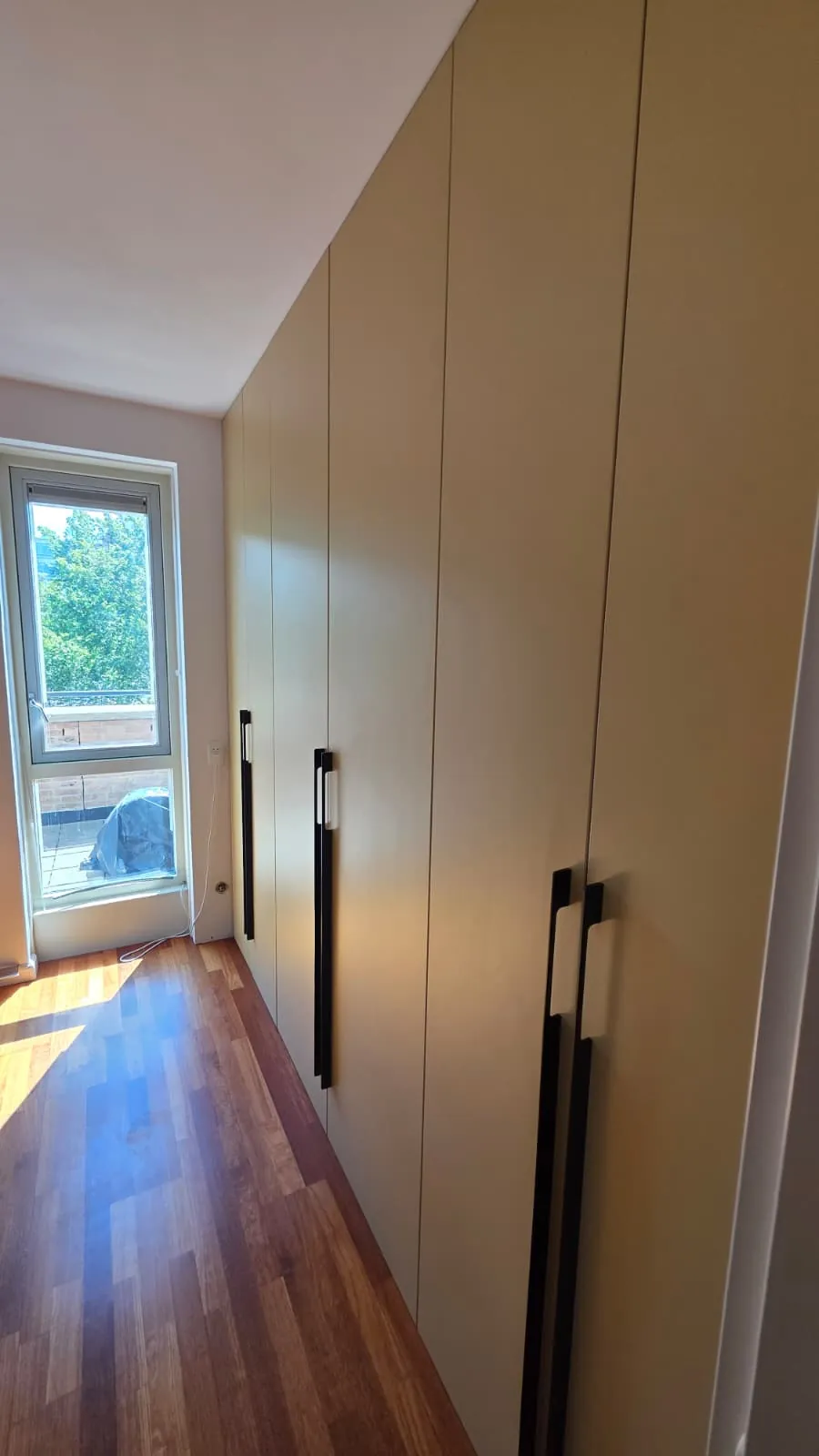 Kamerhoge kledingkast op maat met zwarte grepen onder een schuin plafond, gemaakt door Nocek Maatwerk Studio